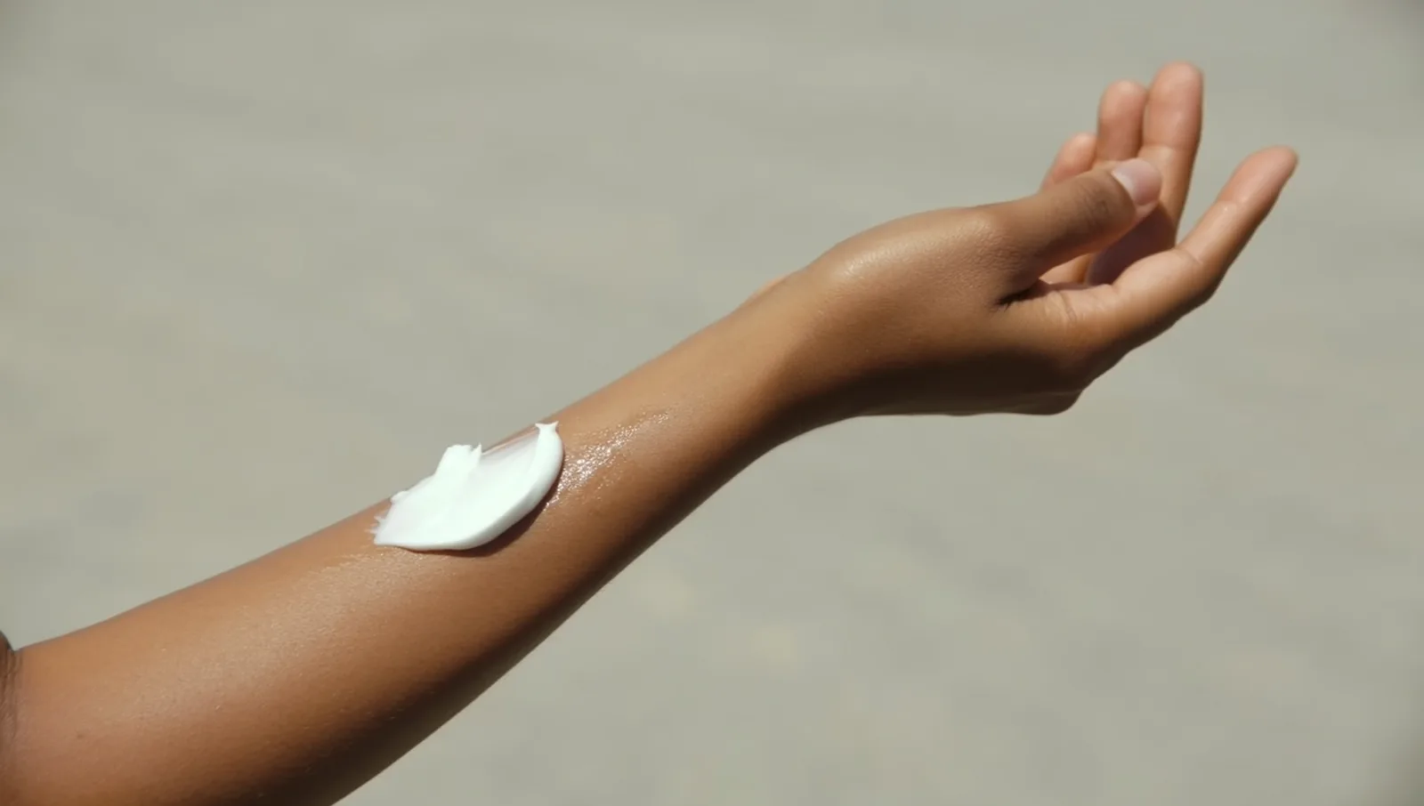 A dab of thick white moisturizing cream on a bare forearm, illustrating the daily emollient routine that underpins eczema care.