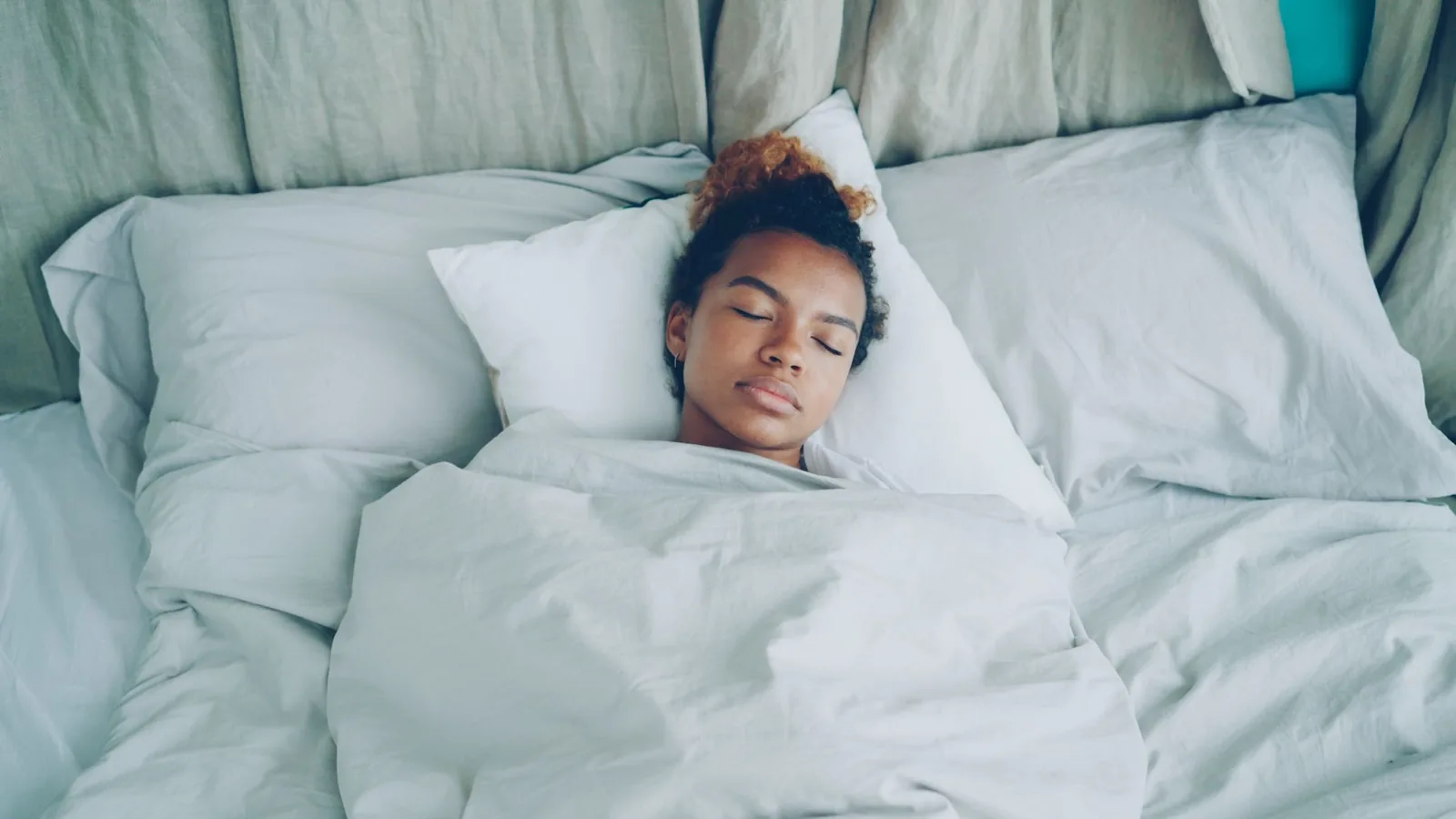 A woman asleep in a bed with white sheets
