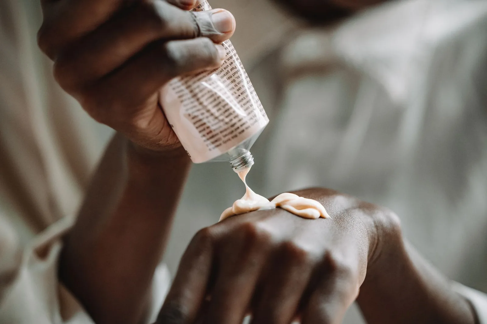 Hands applying moisturizing cream from a tube