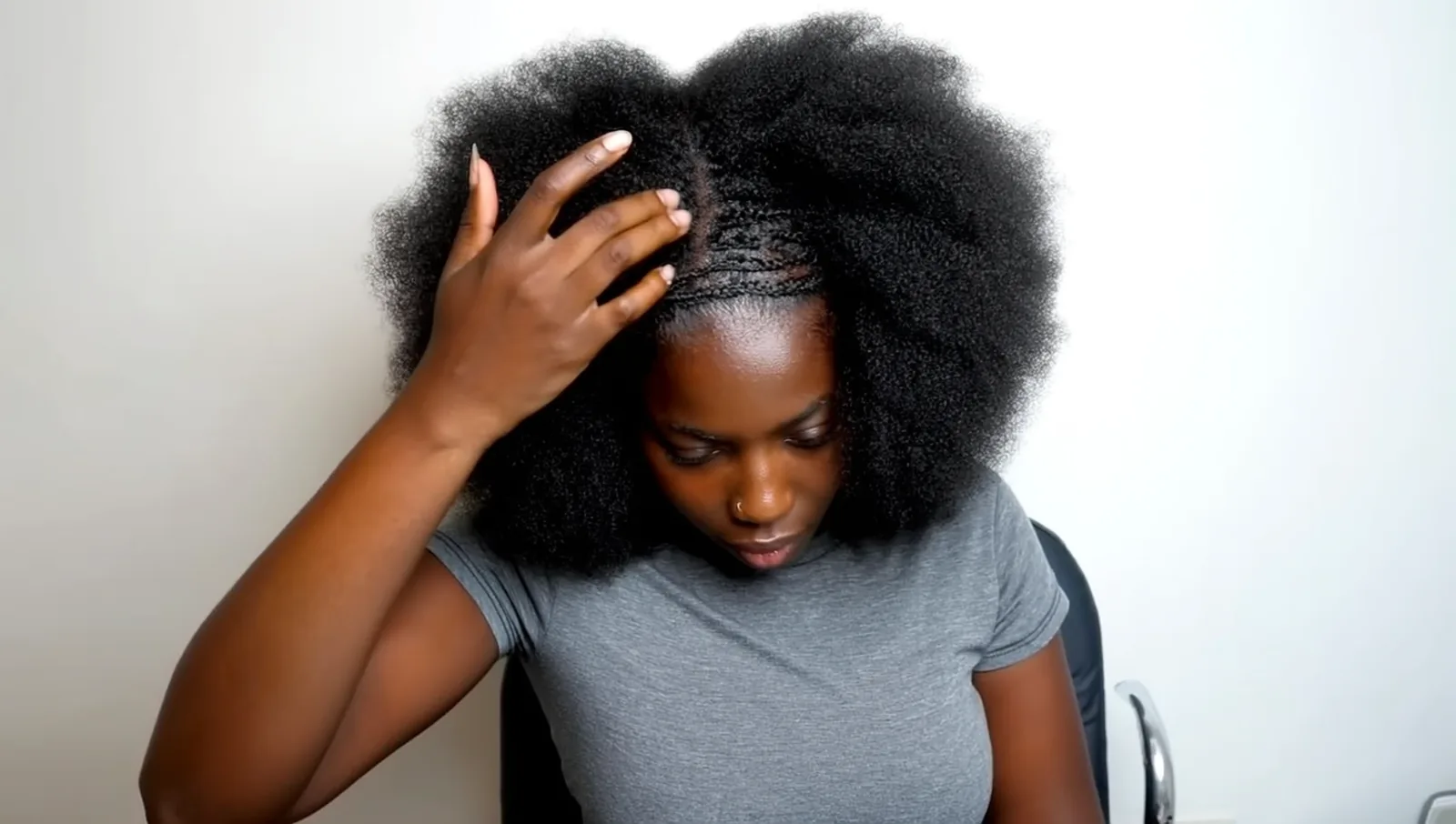 Woman parting coiled hair to see her scalp
